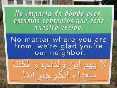 A sign in front of the church that reads "No matter where you are from, we're glad you're our neighbor" in English, Spanish, and Arabic. 